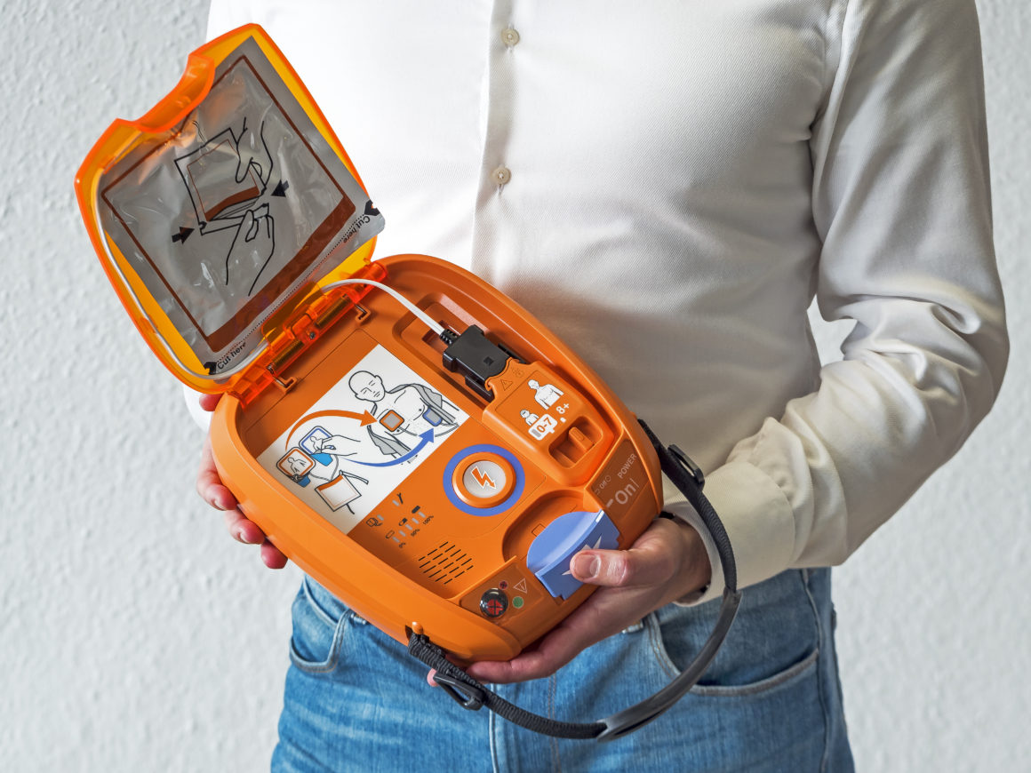 Mitarbeiter mit einem NIHON KOHDEN AED 3100 Defibrillator in der Hand